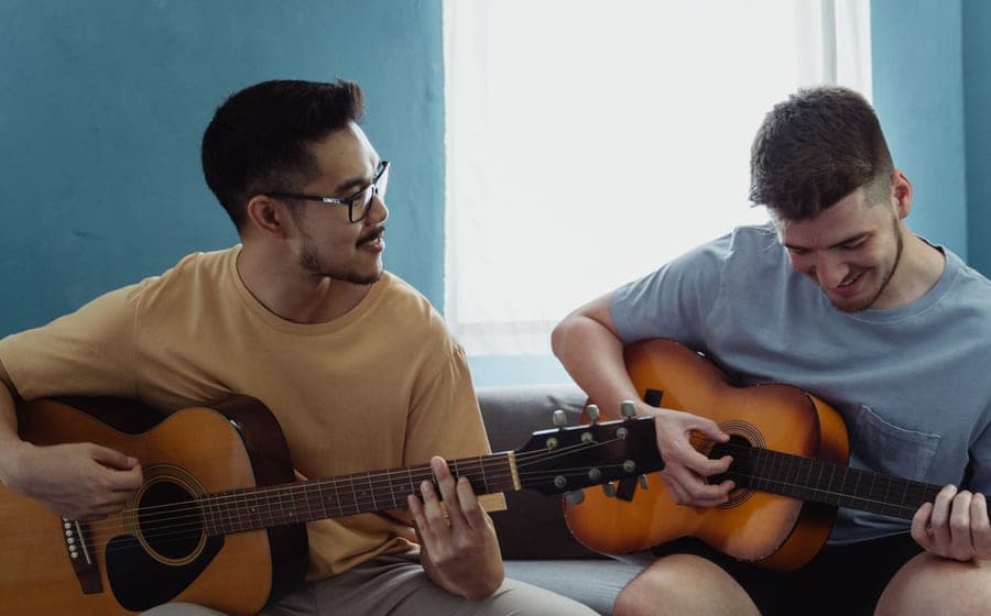 An adult practicing guitar at home