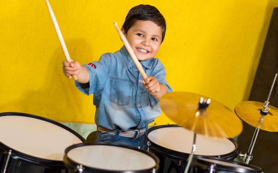 A child sitting at a small drum kit