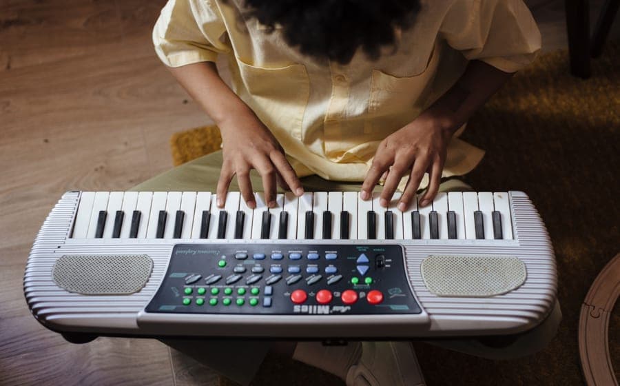 A child sitting at a keyboard practicing at home