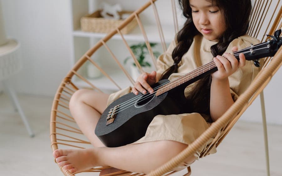 A child playing a small ukulele